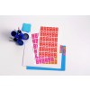 The image features a collection of colorful office supplies including stickers or labels with numbers, stacked sheets of paper, and a blue cup containing various writing instruments and paper clips. There are also sticky notes visible in vibrant colors.