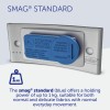 The image displays the SMAG® Standard, a blue magnetic device for holding up to 1 kg, suitable for different fabric types. It includes cautionary instructions for use with cardiac pacemakers in multiple languages.