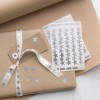 The image features a beautifully wrapped gift in brown paper adorned with silver star stickers and a matching ribbon. There's a gift tag attached, and additional star stickers are placed next to the package.