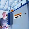 warning label in warehouse with man in background of factory