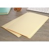 The image shows two yellow file folders placed on a gray wooden desk. In the background, there is a blue notebook and a keyboard visible. The overall setting is organized and appears to be a workspace.