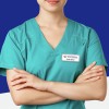 The image shows a person wearing a teal medical scrub top with crossed arms and a name tag. The background is a solid deep blue, making the individual stand out. The name tag indicates the name 'Sarah Baron' and the organization 'Universal Healthcare Corporation.'