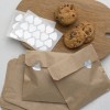 The image features chocolate chip cookies placed on a round wooden cutting board, accompanied by sheets of heart-shaped stickers. In the foreground, there are brown envelopes decorated with heart-shaped cutouts.