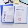 The image shows an open binder with a table of contents on the left page and an introduction on the right. The table of contents lists various sections including introduction, vision-mission, background, sample works, clients, and team. The introduction page provides a description of a business proposal.