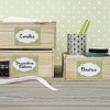 The image shows a neatly organized workspace with wooden boxes labeled 'Candles,' 'Decorative Ribbons,' and 'Elastic.' There’s a decorative cup with pens and various rolls of ribbon nearby, all set against a light polka-dotted background.